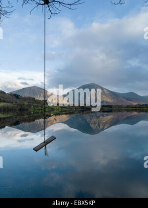 Rope swing with calm, still waters of Loweswater lake and mountain fells beyond, English Lake District, Cumbria, England, UK. Stock Photo