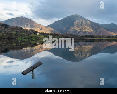 Rope swing with calm, still waters of Loweswater lake with mountain fells beyond, English Lake District, Cumbria, England, UK. Stock Photo