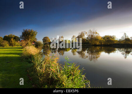 sun shining on a lake shore through a hole in a cloud cover, Germany, Lower Saxony, Vogtlaendische Schweiz, Dorum-Neufeld Stock Photo