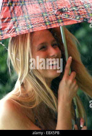 young woman in a bikini in the rain holding an umbrella with a smile Stock Photo