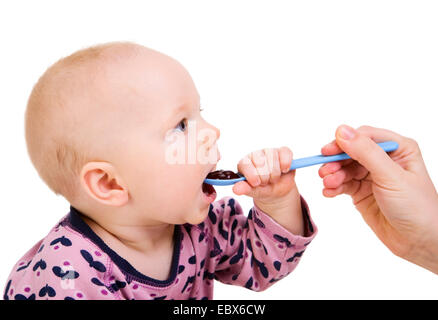 Little girl eating baby food with spoon Stock Photo