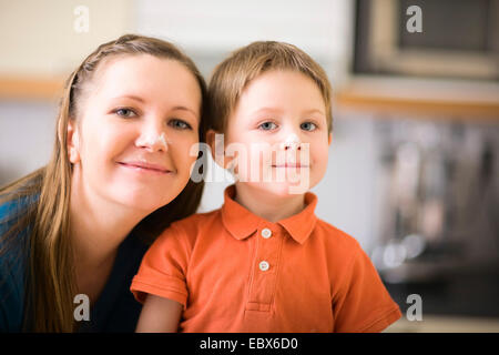 Young mother and son in kitchen making cookies, both with meal on the nose Stock Photo