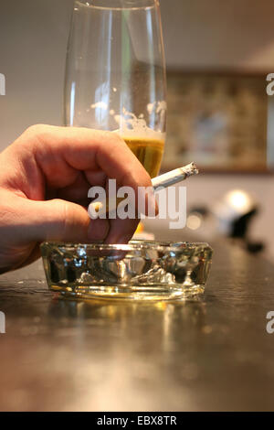 Hands holding cigarettes and beer Stock Photo - Alamy