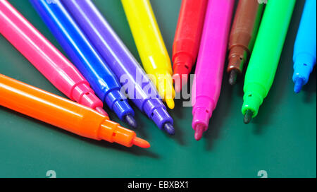 a pile of felt-tip pens of different colors on a green chalkboard Stock Photo
