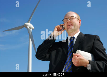 man telephoning with a cellular in front o a wind engine Stock Photo