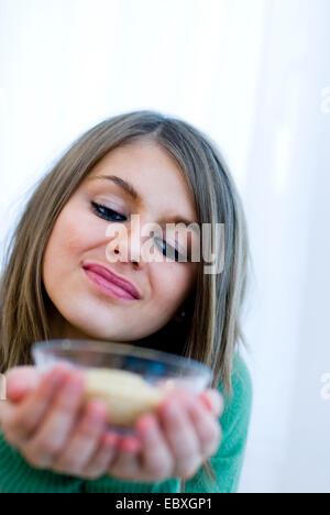 cute blond woman looking at a dessert, she is holding in her hands Stock Photo