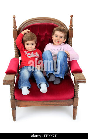 two brother sitting on a velvet armchair Stock Photo