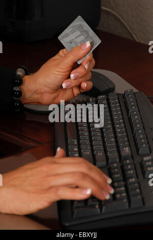 online shopping, Close up detail of a business womans hands holding a credit card and making a purchase on line Stock Photo