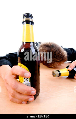 drunken teenager sitting at a desk with beer bottles Stock Photo