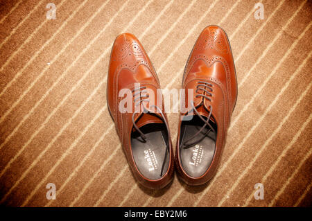 Brown men's shoes against a brown carpet background. Stock Photo