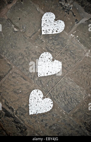 Three vintage wooden wicker hearts on a stone wall background Stock Photo