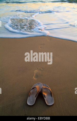 Sandals  and Footprints on the Beach Stock Photo