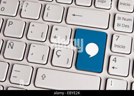 Spanish keyboard with social media message bubble icon over blue background button. Image with clipping path for easy change the Stock Photo