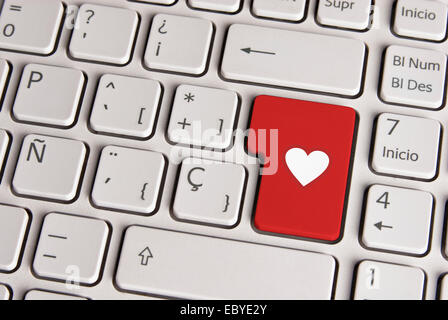 Spanish keyboard with love concept heart shape icon over red background button. Image with clipping path for easy change the key Stock Photo