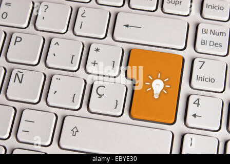 Spanish keyboard with new idea light bulb icon over gold background button. Image with clipping path for easy change the key col Stock Photo