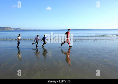 Lyme Regis, Dorset, UK, 6 December 2014: Crowds turn out on a gloriously sunny December day for the Great Lyme Regis Christmas Pudding Race. Runners have to transport a Christmas Pudding around an obstacle course with various Christmas related tasks to complete on route. Credit:  Tom Corban/Alamy Live News Stock Photo