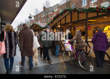 Christmas shoppers in Manchester UK, Festive decorated wooden chalets in St Annes Square. Busy City centre Christmas shops, stalls & market traders. Stock Photo