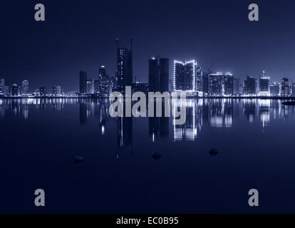 Night modern city skyline with shining lights and reflection in the water. Manama, the Capital of Bahrain, Middle East. Monochro Stock Photo