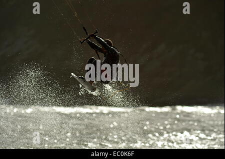 kite surfer in spray silhouetted as he flies  high above the wave Stock Photo