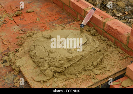 Bricklaying trowel and a board of mortar on a UK building site Stock Photo