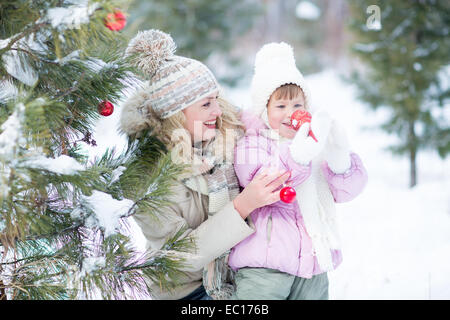 Happy parent and kid playing with christmas tree decorations outdoor Stock Photo