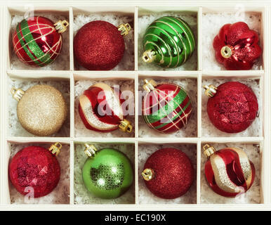 Variety of red, green, and golden Christmas ball ornaments in a wooden box Stock Photo