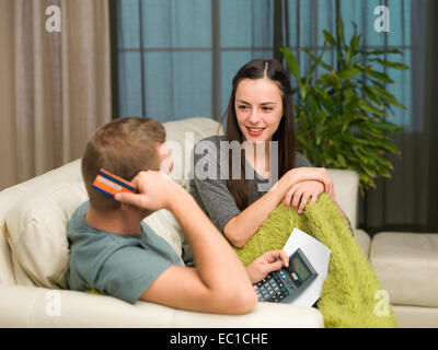 caucasian couple sitting on couch at home calculating payments