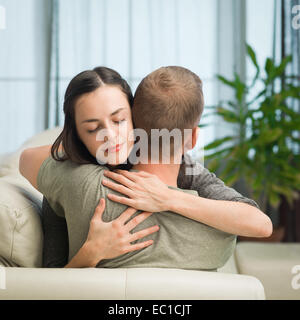 portrait of young caucasian couple relaxing on sofa at home, embracing each other Stock Photo