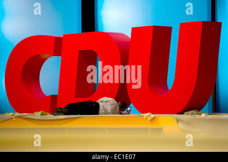 Cologne, Germany. 08th Dec, 2014. A worker removes film from the party logo before the Christian Democratic Union Party federal party convention in Cologne, Germany, 08 December 2014. Photo: ROLF VENNENBERND/dpa/Alamy Live News Stock Photo