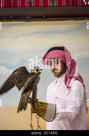 Arab examining falcon in Doha city shop. The falcon is the national bird of United Arab Emirates, Qatar, Saudi Arabia and Oman, a status symbol for royal Arab families. Falconry is a favourite sport in the Arabian Peninsula, maintaining the heritage of the desert. The price of falcons on the Qatari market has soared to more than US$275k, bouoyed by increased domestic demand on the back of a recent festival. Stock Photo