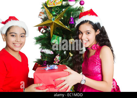 2 indian friend Christmas Tree giving gift Stock Photo