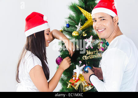 indian friend Christmas Tree  Tying gift Stock Photo