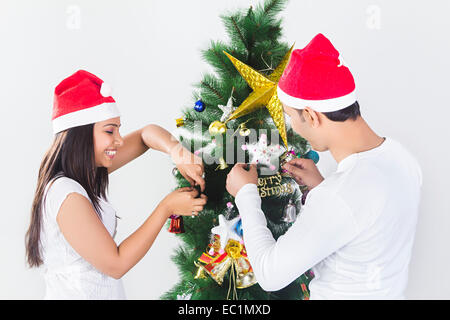 indian friend Christmas Tree  Tying gift Stock Photo