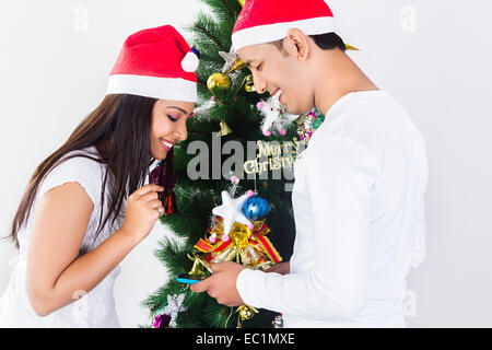 indian friend Christmas Tree  Tying gift Stock Photo