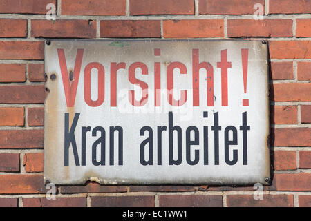 Vorsicht Kran arbeitet retro sign on brick wall Stock Photo