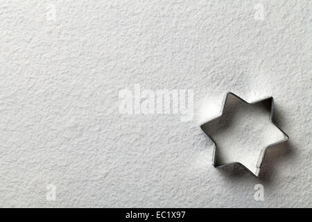 Christmas cookie mold in shape of star on flour background. Copy space. White flour looks like snow. Top view Focus on mold edge Stock Photo