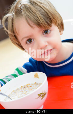 Little Boy eating cereal with milk and gets dirty Stock Photo