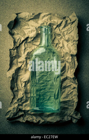 Blue green glass bottle on a crumpled paper background. Stock Photo