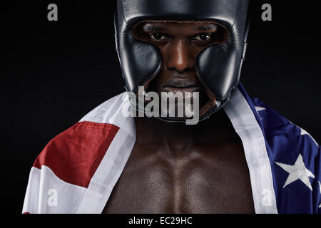 Close-up portrait of young male wearing boxing helmet with American flag against black background