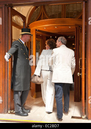 An older couple arriving leaving a hotel lobby entrance Stock Photo