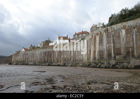 Tall concrete sea defences at Robin Hood's Bay, a small fishing village and coastal bay with a Jurassic cliff coastline on the Stock Photo