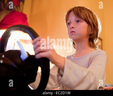 Boy Playing Racing Console Game with Steering Wheel Stock Photo