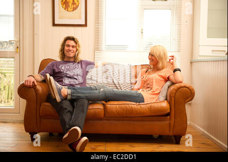 A young couple relaxing on a leather sofa Stock Photo