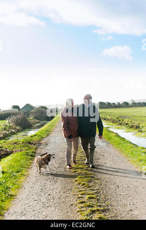 An older couple walking their dog in the countryside Stock Photo