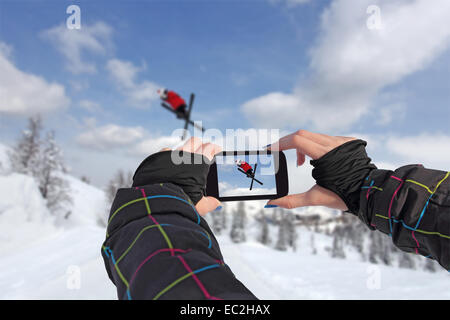 A young girl by mobile phone photographed of skiers jump Stock Photo