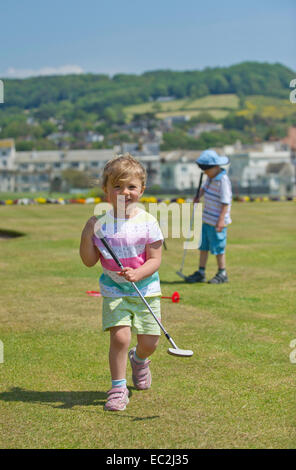 A young girl and boy playing golf by the seaside Stock Photo