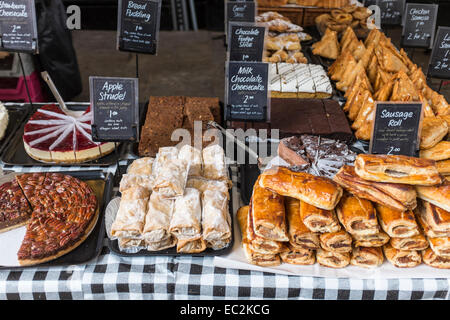 Cakes, pastries and sausage rolls on display for sale on a market stall. Stock Photo