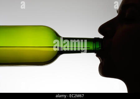 Silhouette of a woman drinking wine from a bottle Stock Photo