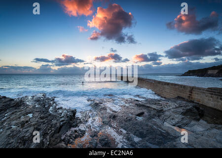 Dramatic sunset and waves at the pier in Porthleven harbour on the Cornwall coast near Helston Stock Photo