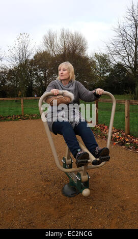 November 2014 - Mature lady on an outdoor exercise machine in New Barn Park, Swanley, Kent, England, UK GB Stock Photo